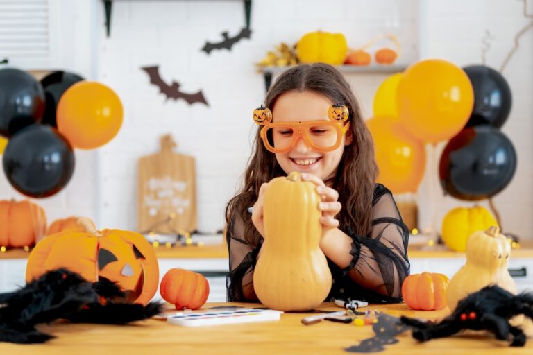 Halloween, a child in a witch costume is preparing for the Halloween holiday by coloring pumpkins at home in the kitchen with festive props, happy Halloween, blog