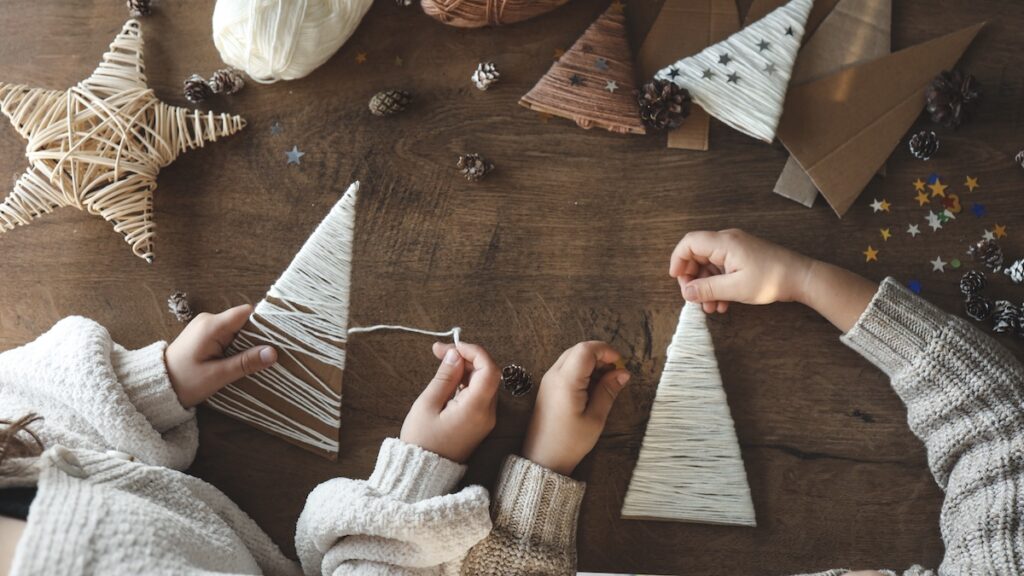 One of 10 Fun Christmas Activities for Kids to Make the Season Magical - two children creating cardstock Christmas trees together