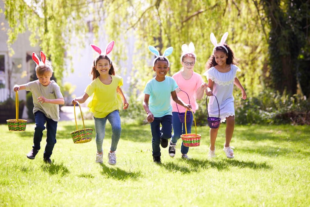 Easter outdoor activities for kids, Group Of Children Wearing Bunny Ears Running To Pick Up Chocolate Egg On Easter Egg Hunt In Garden